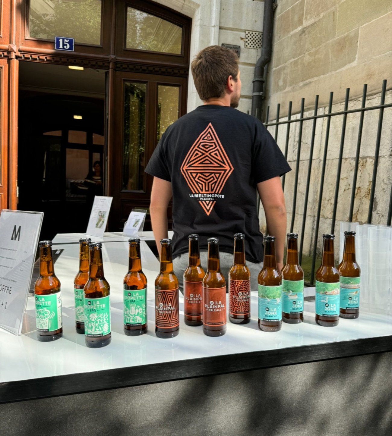 Stand La Meltingpote avec un assortiment de bières artisanales genevoises, incarnant l'esprit de proximité et l'authenticité genevoise lors d'un événement en plein air.