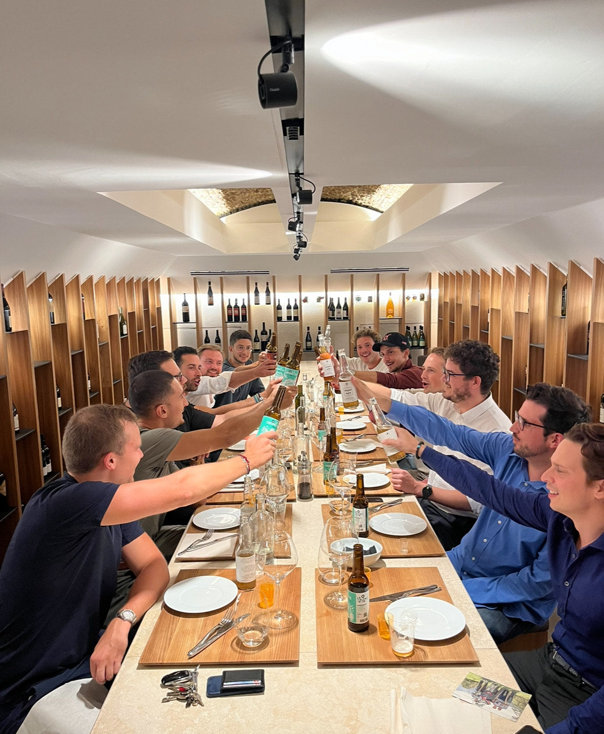 Moment convivial autour d'une grande tablée, des amis trinquant avec des bières artisanales genevoises, créant des souvenirs inoubliables autour de saveurs locales.